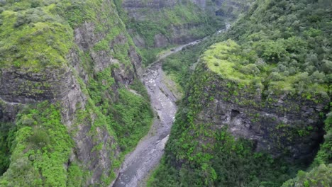 drone footage flying over a river in a green canyon in the cirque of mafate on the reunion island