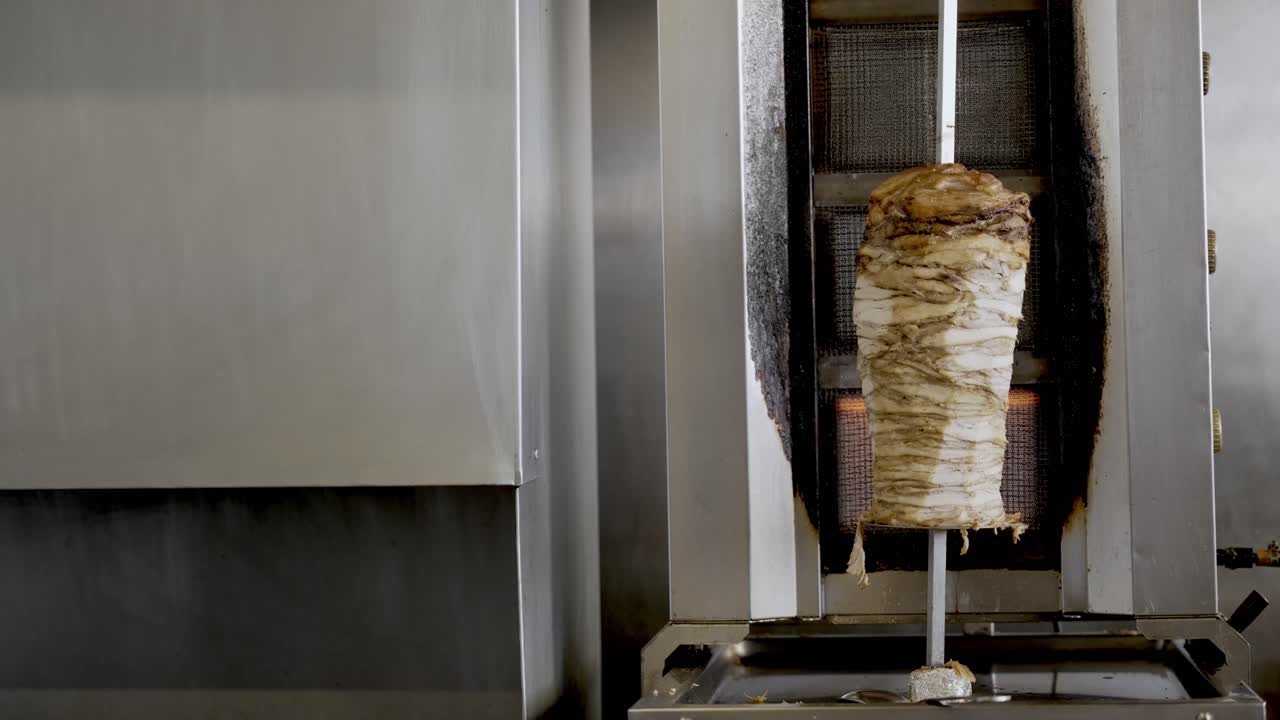 Grande spiedo di shawarma di pollo appeso alla griglia che gira