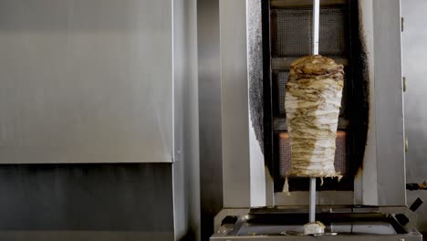 big chicken shawarma skewer hanged on grill turning around