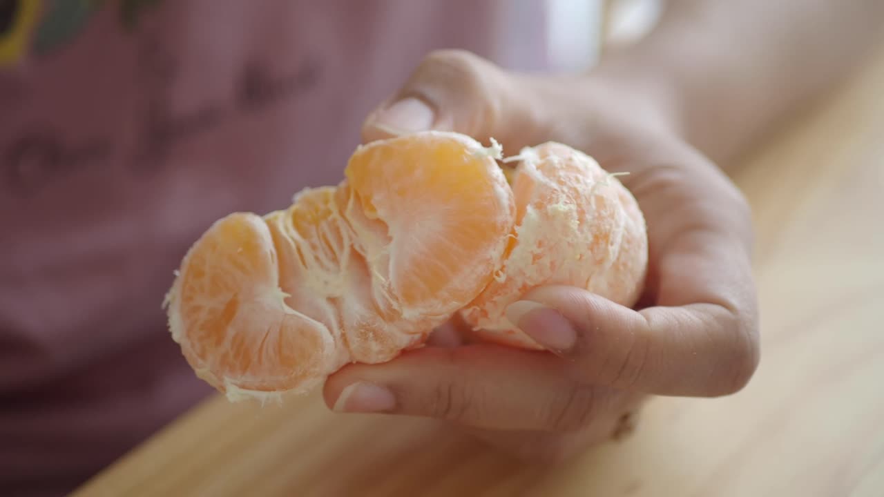 Close-up de mãos descascando uma tangerina fresca