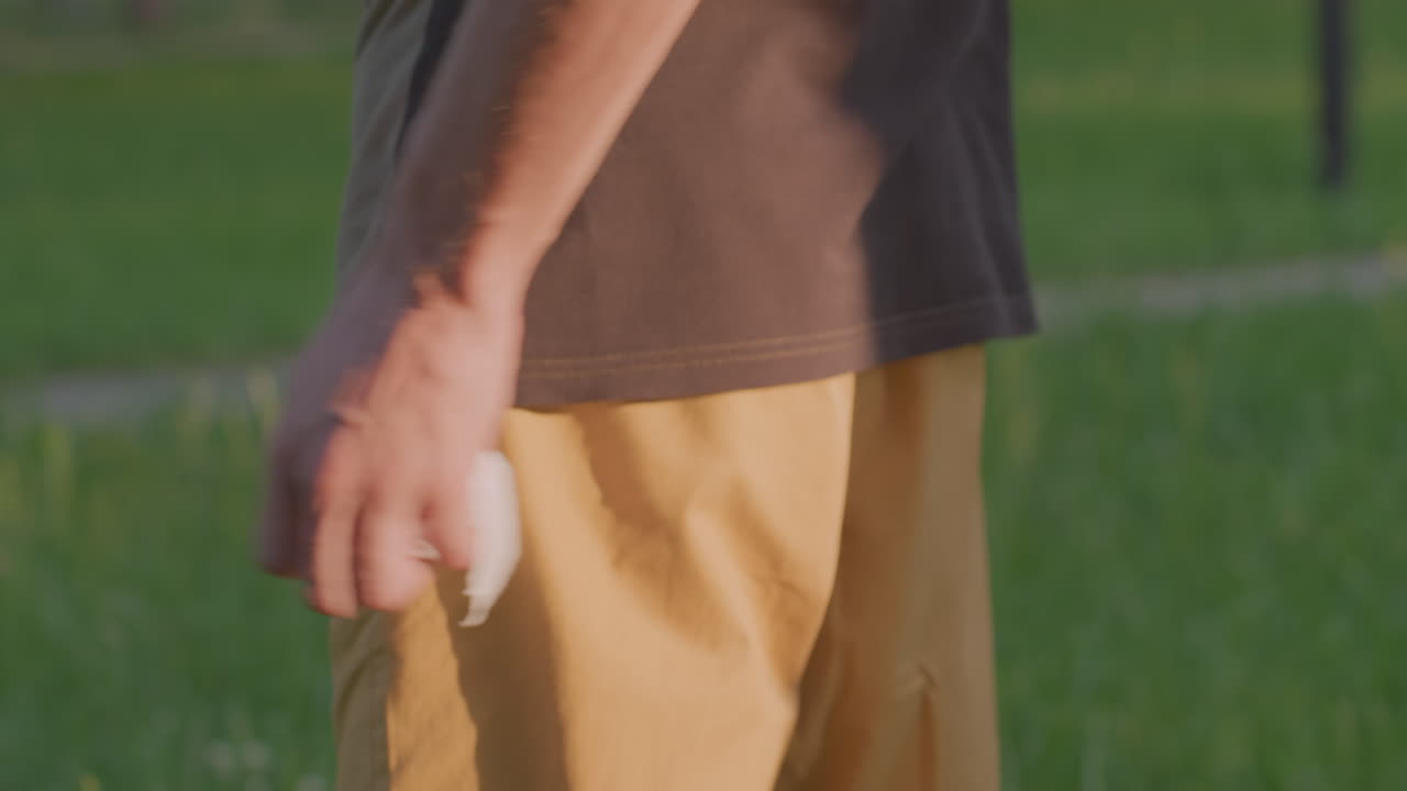 Secretive Tissue Stashing, Man Hides Tissue With Discreet Movements, Subtle Gesture Of Concealment In Peaceful Park Scene, Man Secretly Hides Tissue In Pocket During Serene Park Visit