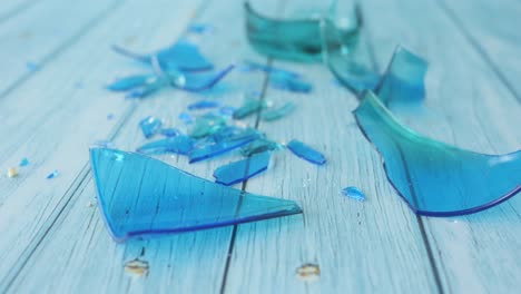 close-up of broken blue glass on a light blue wooden surface