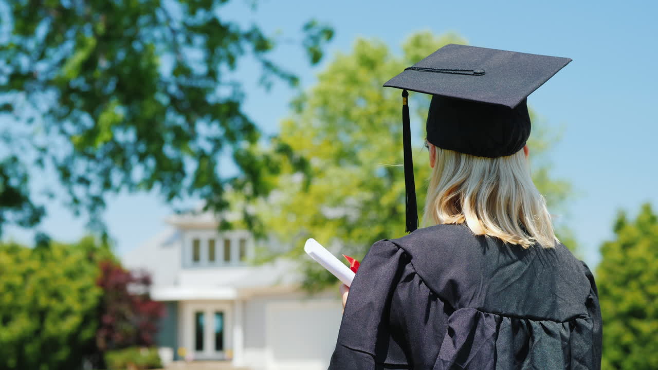 vista trasera de una mujer en un manto y gorra de graduación sosteniendo un diploma en la mano contra el backgrou