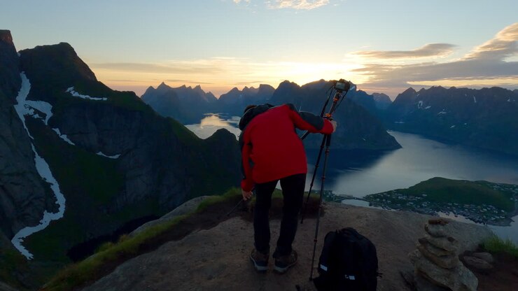 Asian tourist setting up his camera on a scenic peak of Reinebringen to take photos