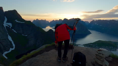 turista asiático configurando su cámara en un pico escénico de reinebringen para tomar fotos