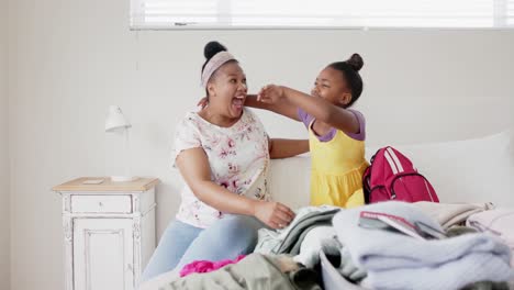 Emocionada-Madre-E-Hija-Afroamericanas-Inalteradas-En-El-Dormitorio-Empacando-Y-Abrazando,-Cámara-Lenta