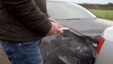 man sending text message after car accident on country road