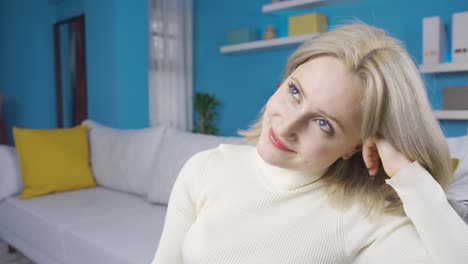 Young-Woman-sitting-alone-at-home-thinking-about-happy-moments-and-smiling.