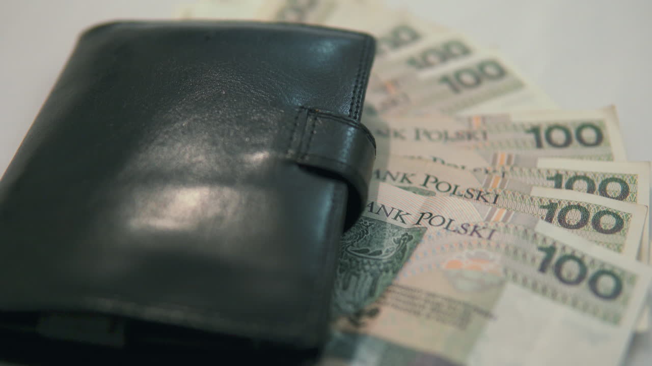 Inclinação: 100 zloty poloneses com carteira preta, tomada com foco no detalhe.
