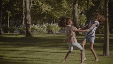 joyful adorable sisters spinning in circle outdoors