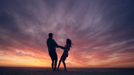 Feliz-Pareja-Bailando-En-La-Playa-Disfrutando-De-Su-Luna-De-Miel-En-La-Naturaleza-Al-Atardecer-Siluetas-De-Un-Dragón-Rojo-De-Tiro-Amplio