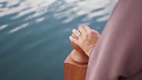 woman with ring holding a rail with a sea view