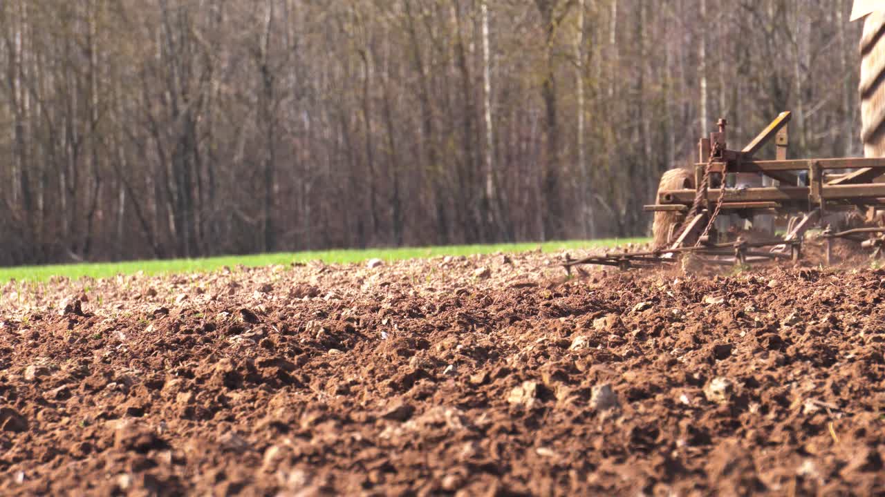 agricultor utiliza equipos de tractor viejos para cultivar el suelo marrón de las tierras de cultivo, letonia