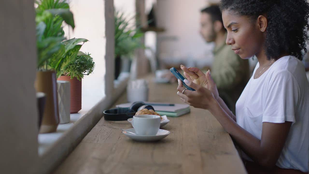 mujer afroamericana feliz usando un teléfono inteligente en un café navegando por mensajes en línea disfrutando de compartir su estilo de vida en las redes sociales relajándose en un restaurante de cafetería
