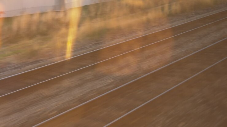 Vista dal finestrino di un treno pendolare. Osservando i binari in movimento al tramonto.