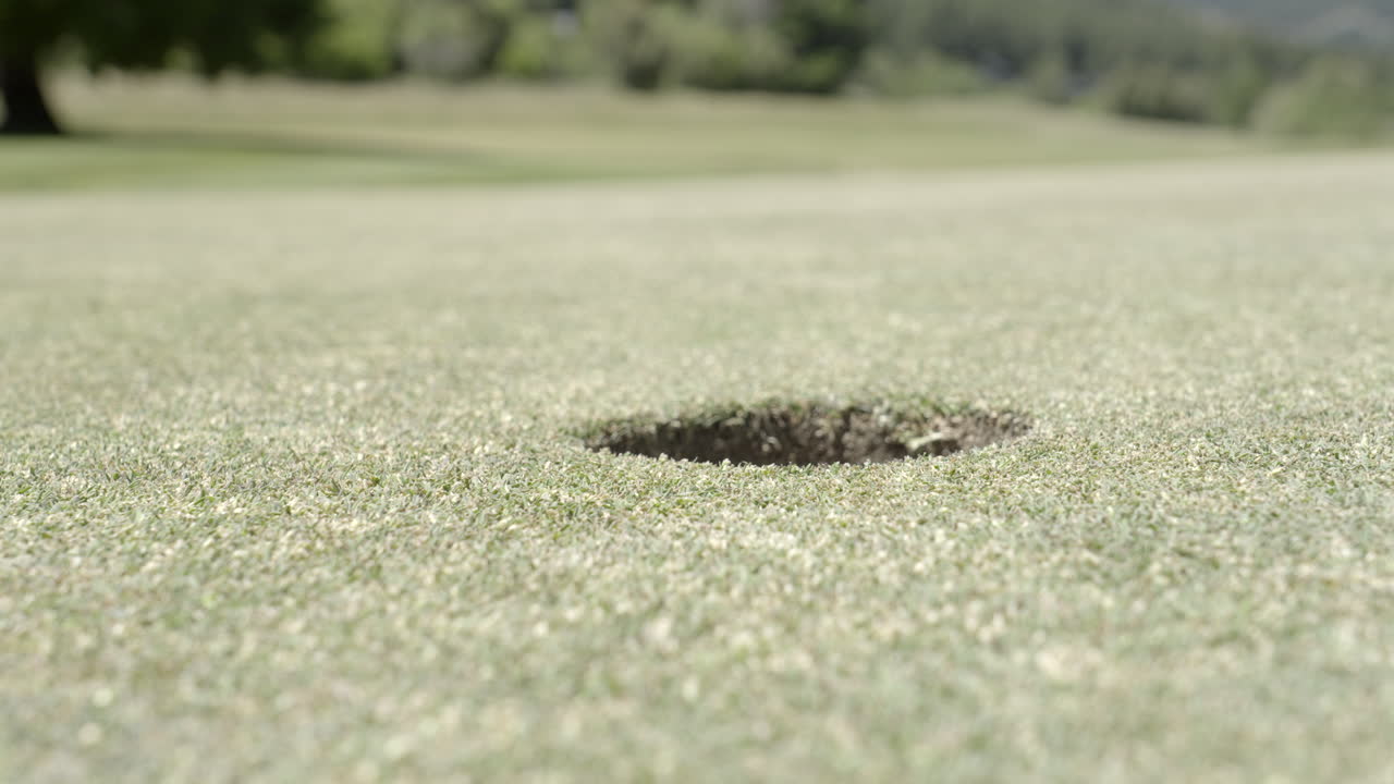 Golf ball rolling into the hole on green