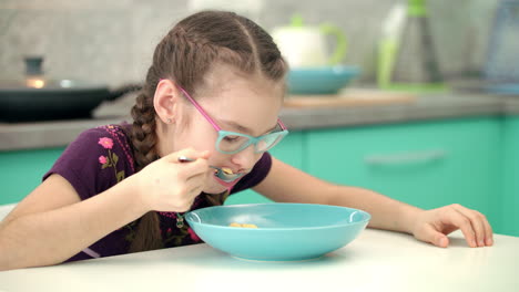 Niña-Comiendo-Copos-De-Maíz-En-La-Cocina.-Retrato-De-Niño-Comiendo-Comida-Sana