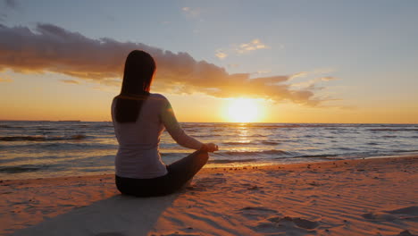 no stress calm young woman sitting in a lotus position on the beach at sunset