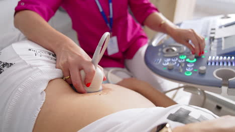 young pregnant woman getting ultrasound from female doctor in clinic. pregnancy and healthcare concept. prenatal screening.