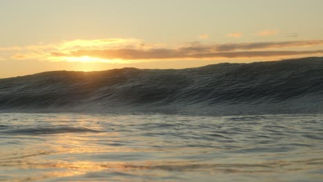 el brillo dorado del sol naciente cuando una ola corta y pesada se estrella