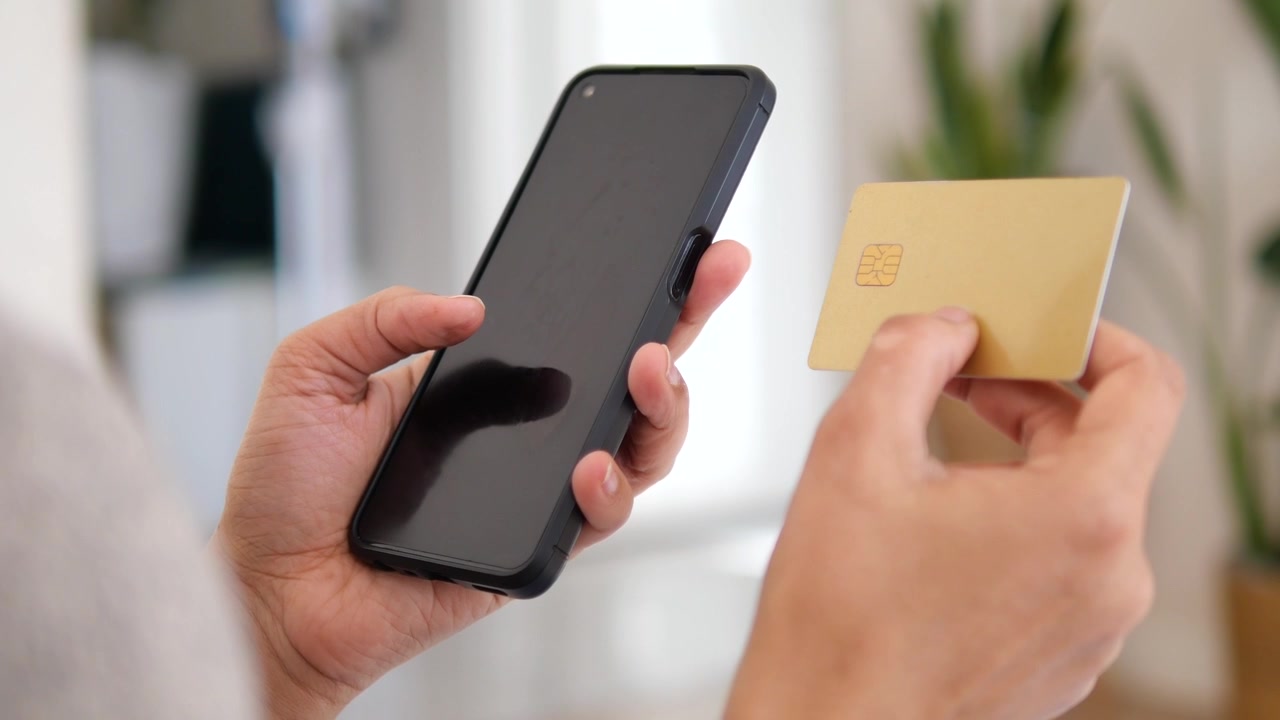 Primo piano di mani che usano smartphone e carta di credito per una transazione online