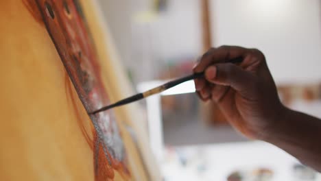 Close-up-of-male-artist-painting-on-canvas-at-art-studio