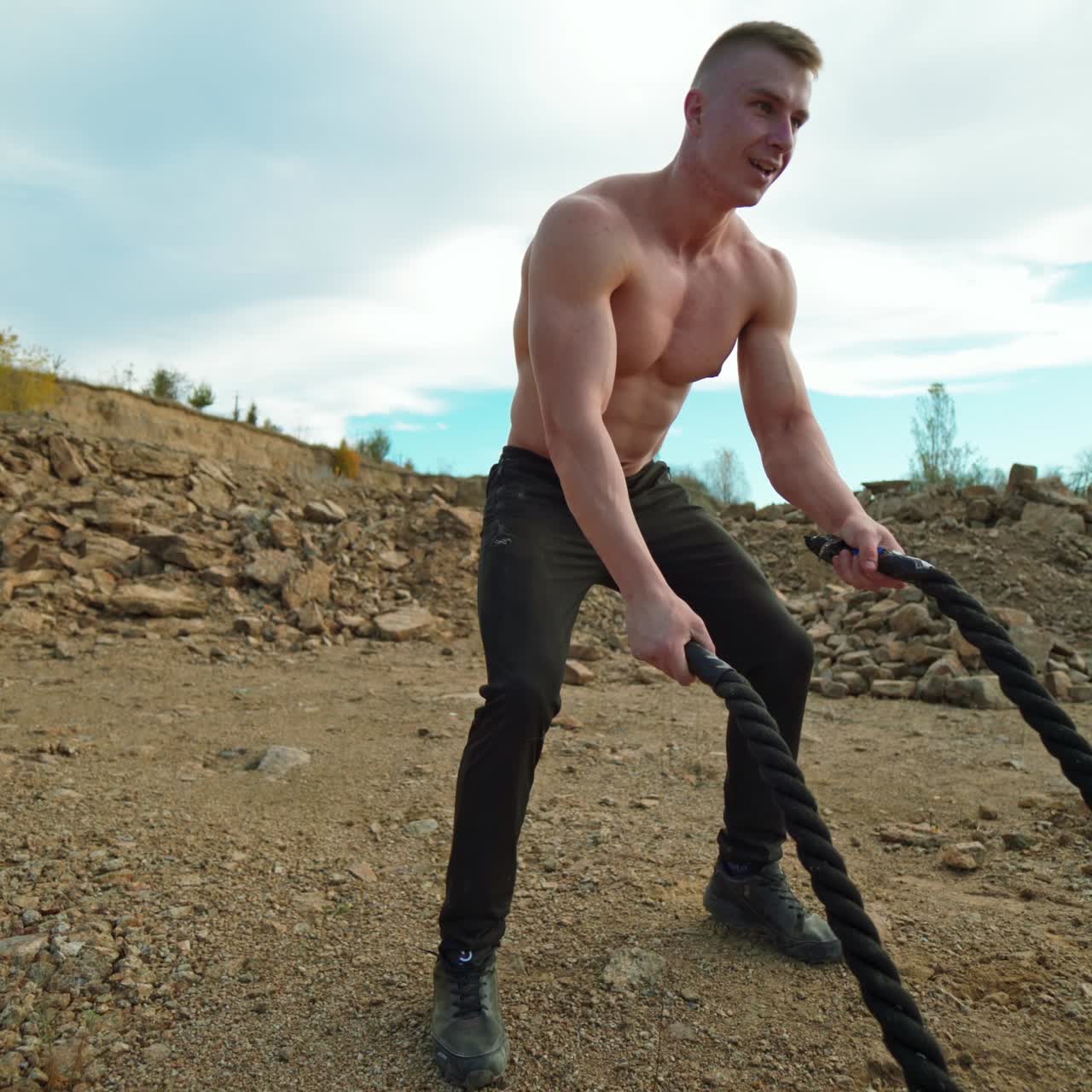 . Athlete doing battle rope workout. Muscular young man working out with battling ropes