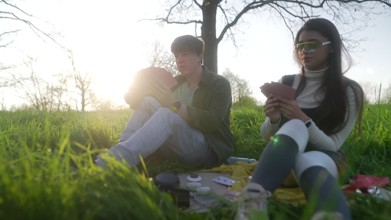 Couple Playing Cards in a Park at Sunset