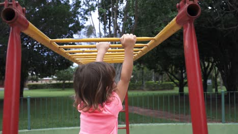 niña de cuatro años jugando en el gimnasio de la jungla colgando de las barras mostrando gran habilidad y habilidad