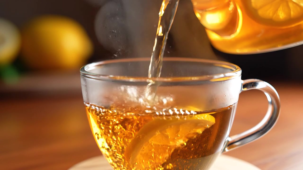 Versare tè caldo con fette di limone in una tazza di vetro