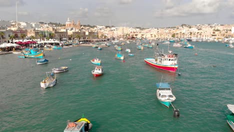 low shot of colorful boats and white seaside houses on a sunny day in malta