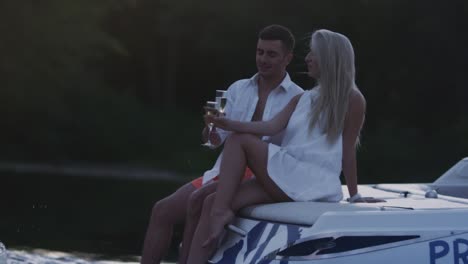 young people toasting with champagne glasses on motor boat. romantic dating