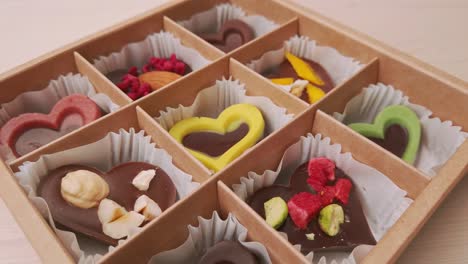 chocolate candies in crafting gift box turns extreme close up. 4k closeup footage of camera slowly moving between assorted chocolates confectionery on the white background