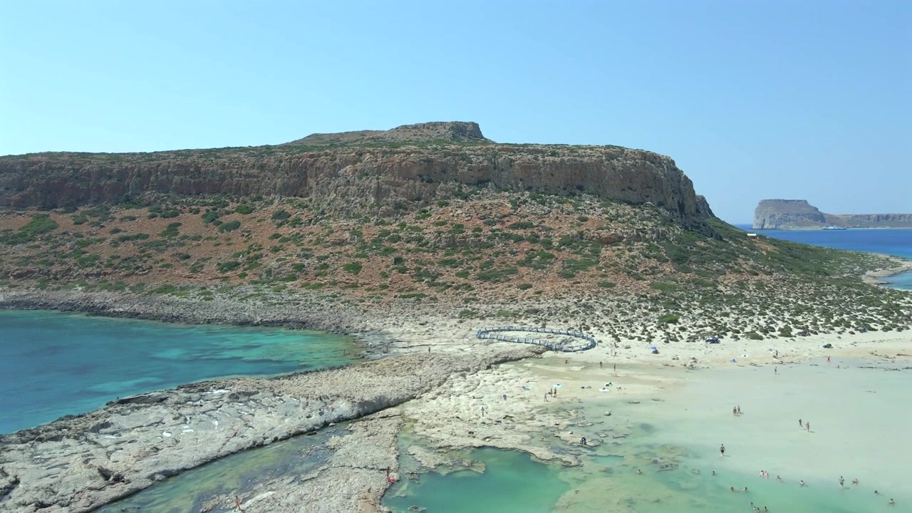 Ripresa panoramica all'indietro con drone che rivela il bellissimo contrasto tra le scogliere dell'isola di Gramvousa, la sabbia bianca e l'acqua turchese della laguna di Balos a Creta, Grecia. Paesaggio paradisiaco esotico, di giorno