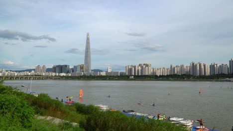 paddle boating and windsurfing at hangang river in seoul with lotte world tower and jamsil bridge in background