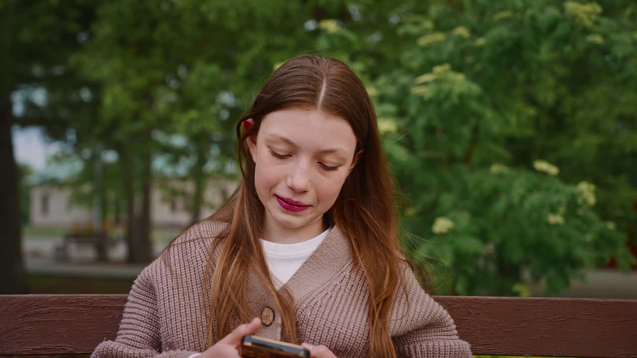 Teenage girl using a phone in a park