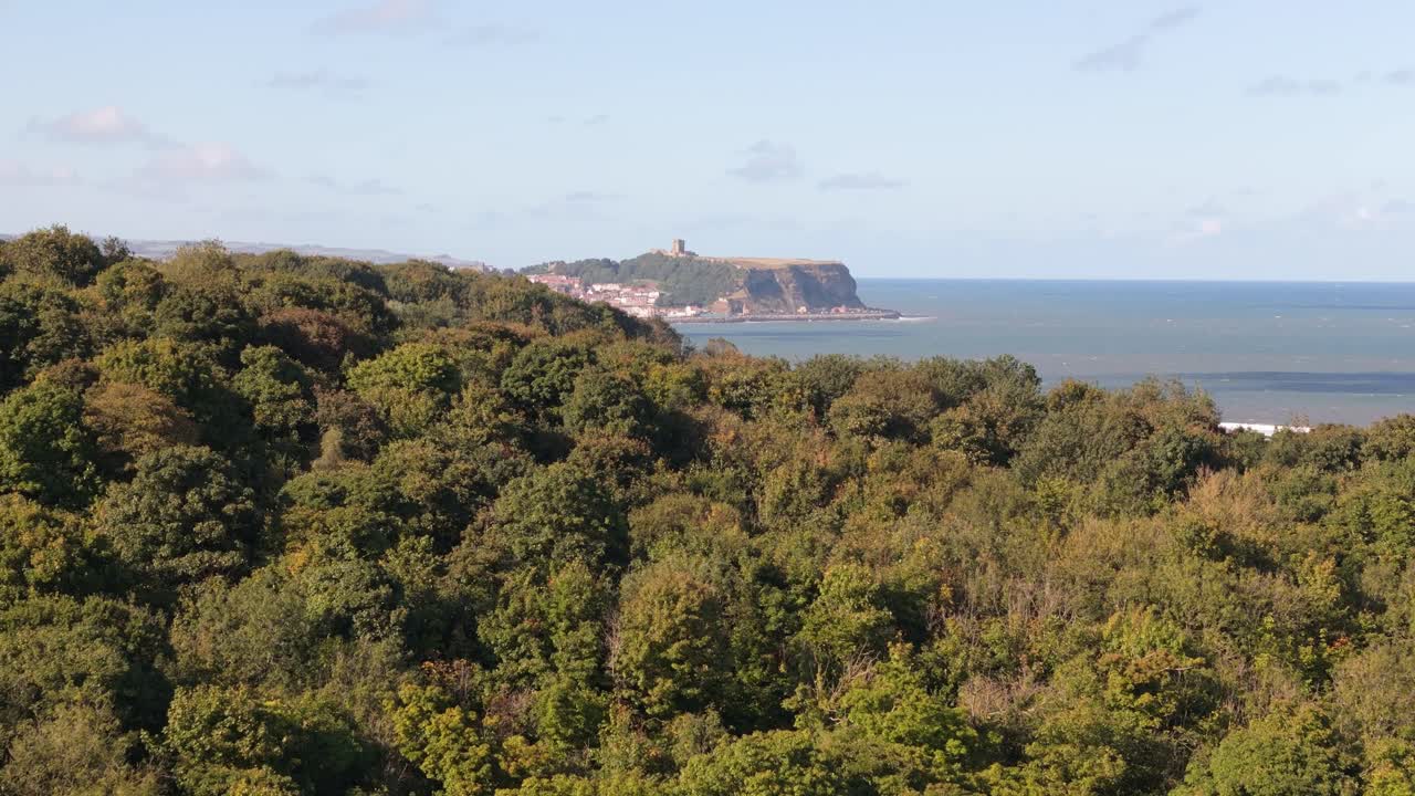 aerial drone footage of Scarborough taken from a distance away over Cayton Bay with blue sky and ocean and big waves