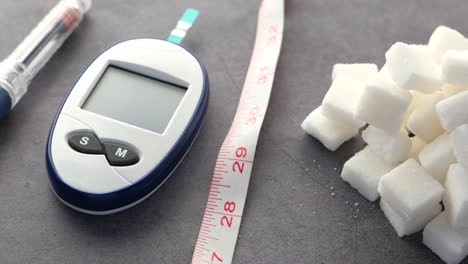 diabetes management: glucose meter, sugar cubes, and measuring tape