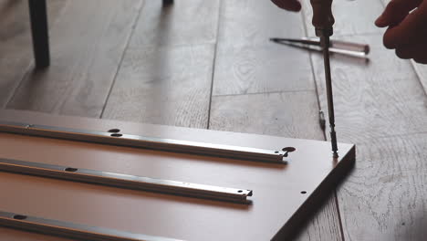 Close-Up-Of-Boy-Hand-Building-A-Shelf,-Screws-In-Screw-On-The-Floor