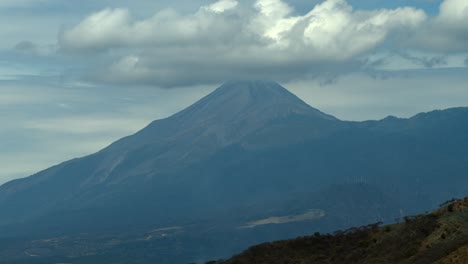 majestic colima volcano with its symmetrical cone and forested lower slopes beneath a cloudy sky near the jalisco colima border. slow drone motion aerial