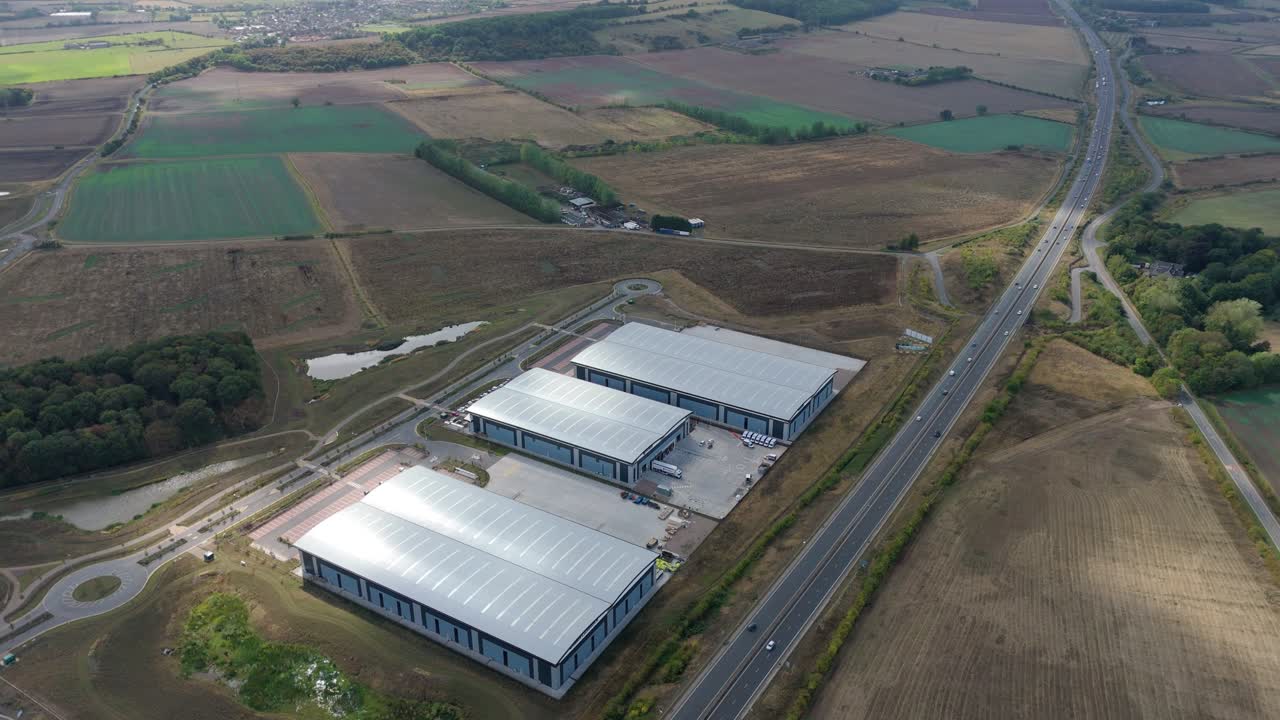 Cinematic aerial view of industrial zone with logistics hubs and rural terrain near Nottingham, UK