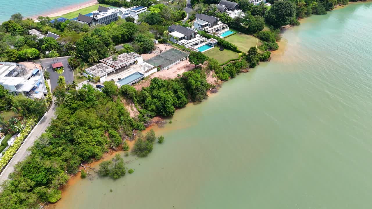 Imagens de drone capturam um resort de luxo com villas sereno e deserto em Phuket, Tailândia, exibindo vegetação exuberante e vistas costeiras.