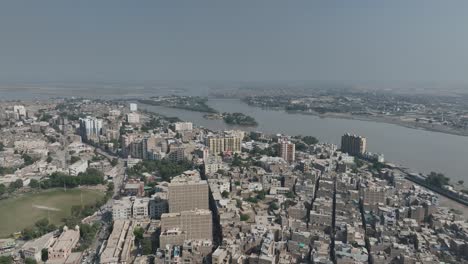 Drone-Sobrevuela-La-Ciudad-De-Casas-Altas-De-Sukkur-Y-El-Río-Indo-Al-Fondo