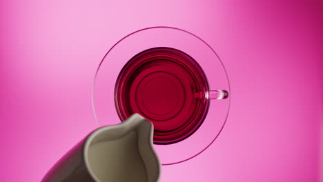 pouring milk into a cup of red tea