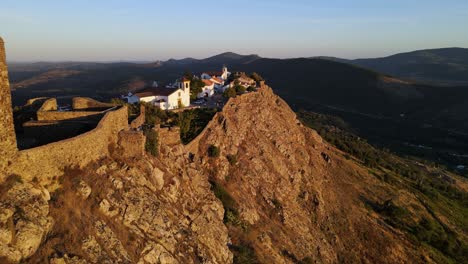 a drone flies past birds towards a white church near marvão castle