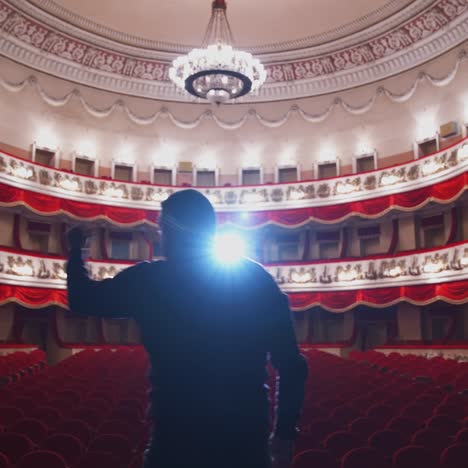 man on stage in empty theater. back view of an actor standing on stage and performing in a large theater without people.