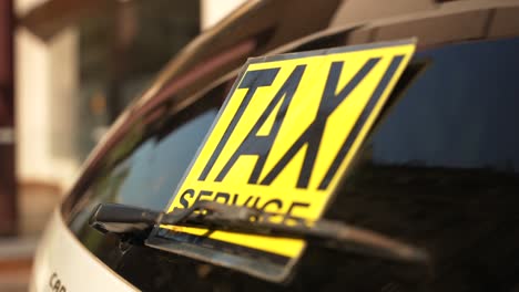 yellow taxi service sticker on the rear window of the car on the parking in the public space