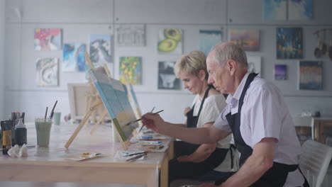 slow motion old people attend drawing courses. the teacher helps pensioners who attend drawing courses to draw. a group of retired friends at a drawing lesson