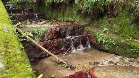 Decorative-cascade,-made-of-stone-surrounded-by-moss-slow-zen-water-stream-in-Japan