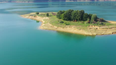lago rama en bosnia y herzegovina con isla erosionada con un grupo de árboles, toma aérea de carro